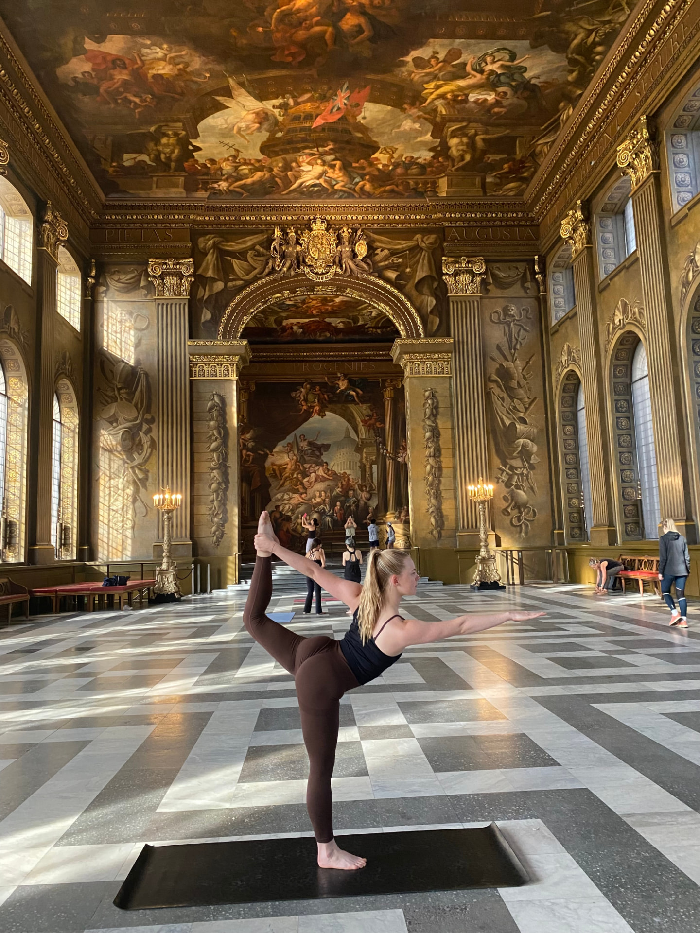 Abbie in a standing balance pose inside a grand painted hall