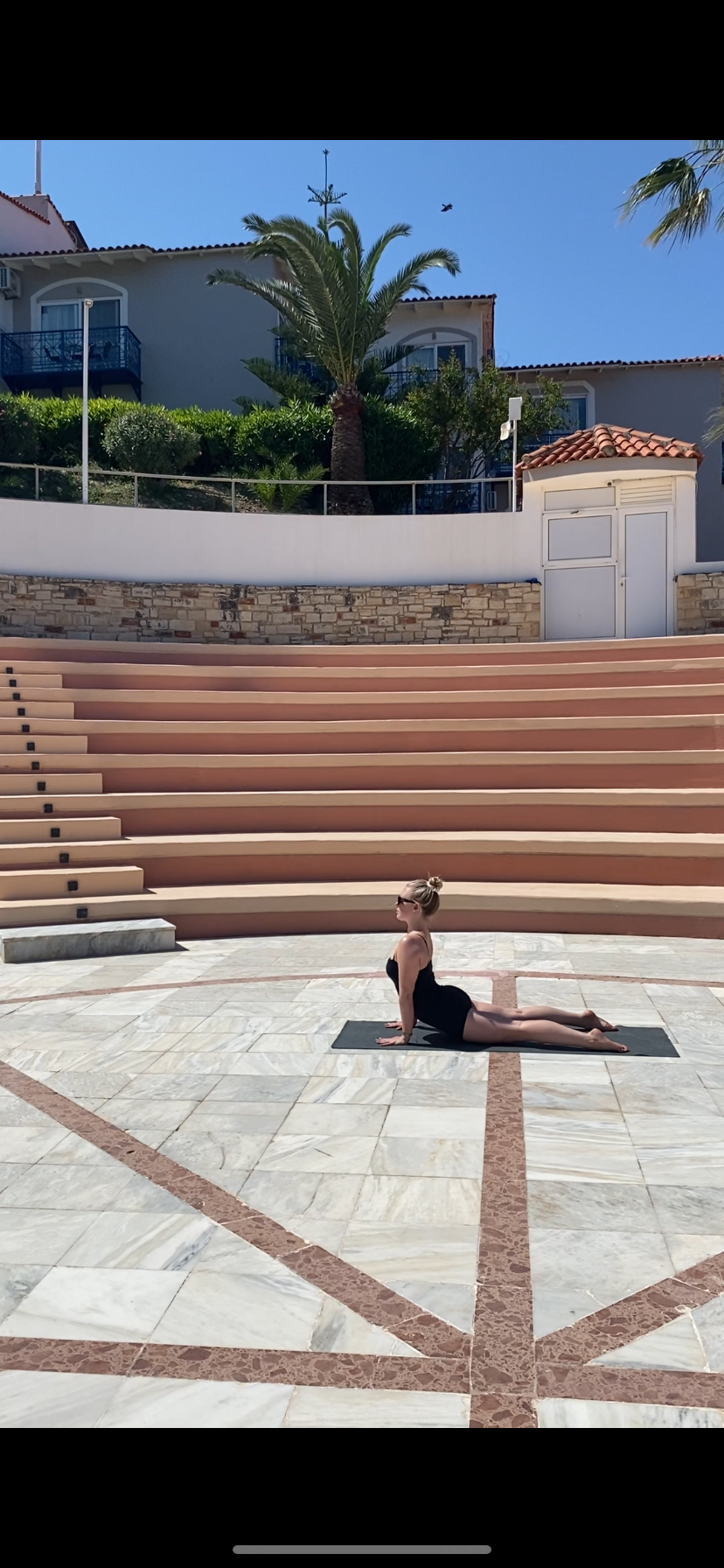 Abbie practising cobra pose in a sunlit stone amphitheatre
